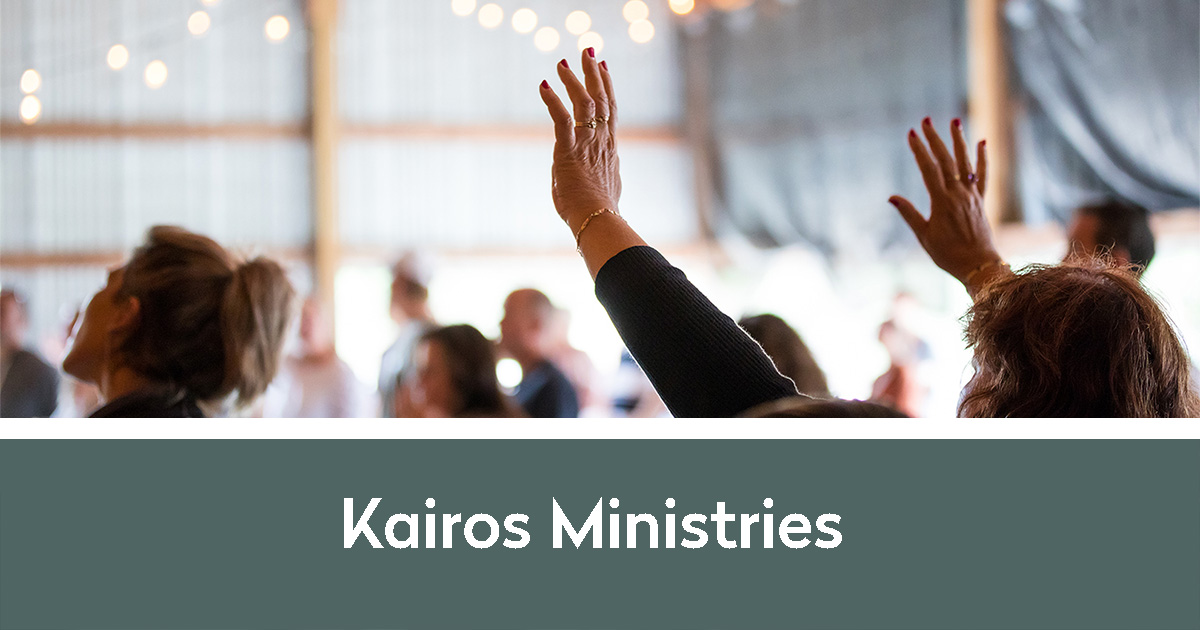Kairos Ministries | People raising hands, worshiping in a bright barn